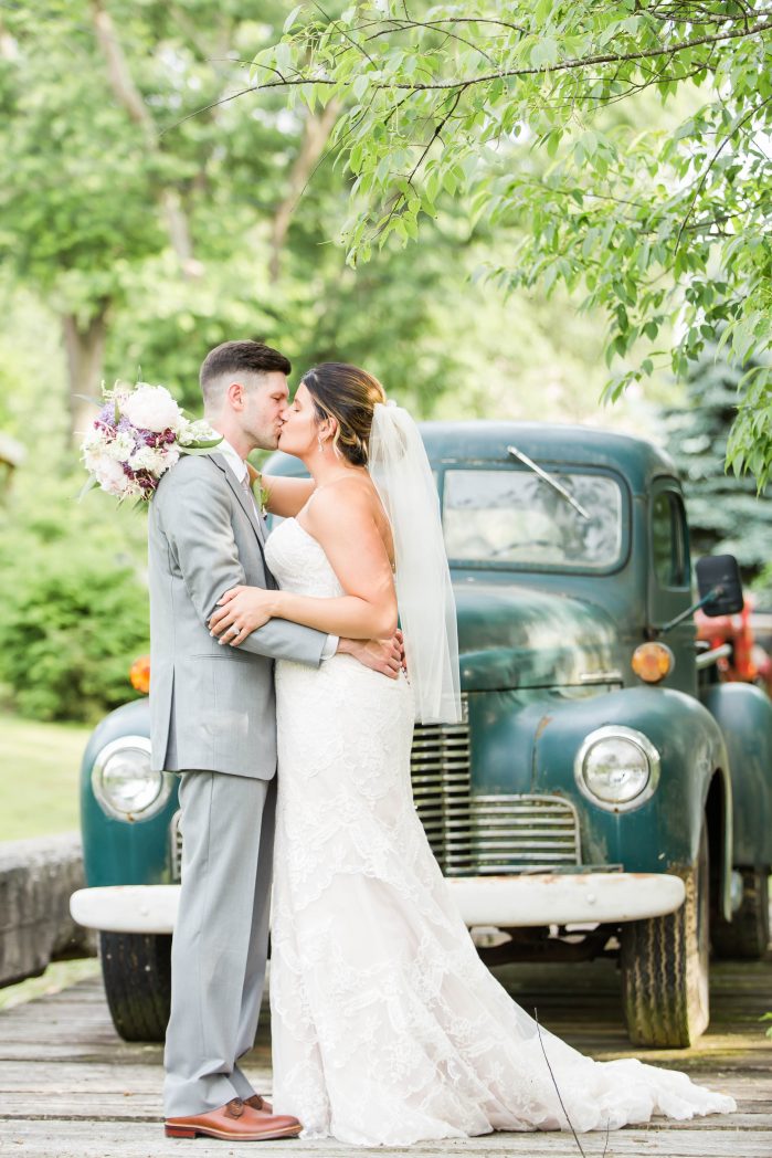 Bride and Groom kissing in front of old green truck at Rivercrest Farm Wedding Photographer Akron Ohio
