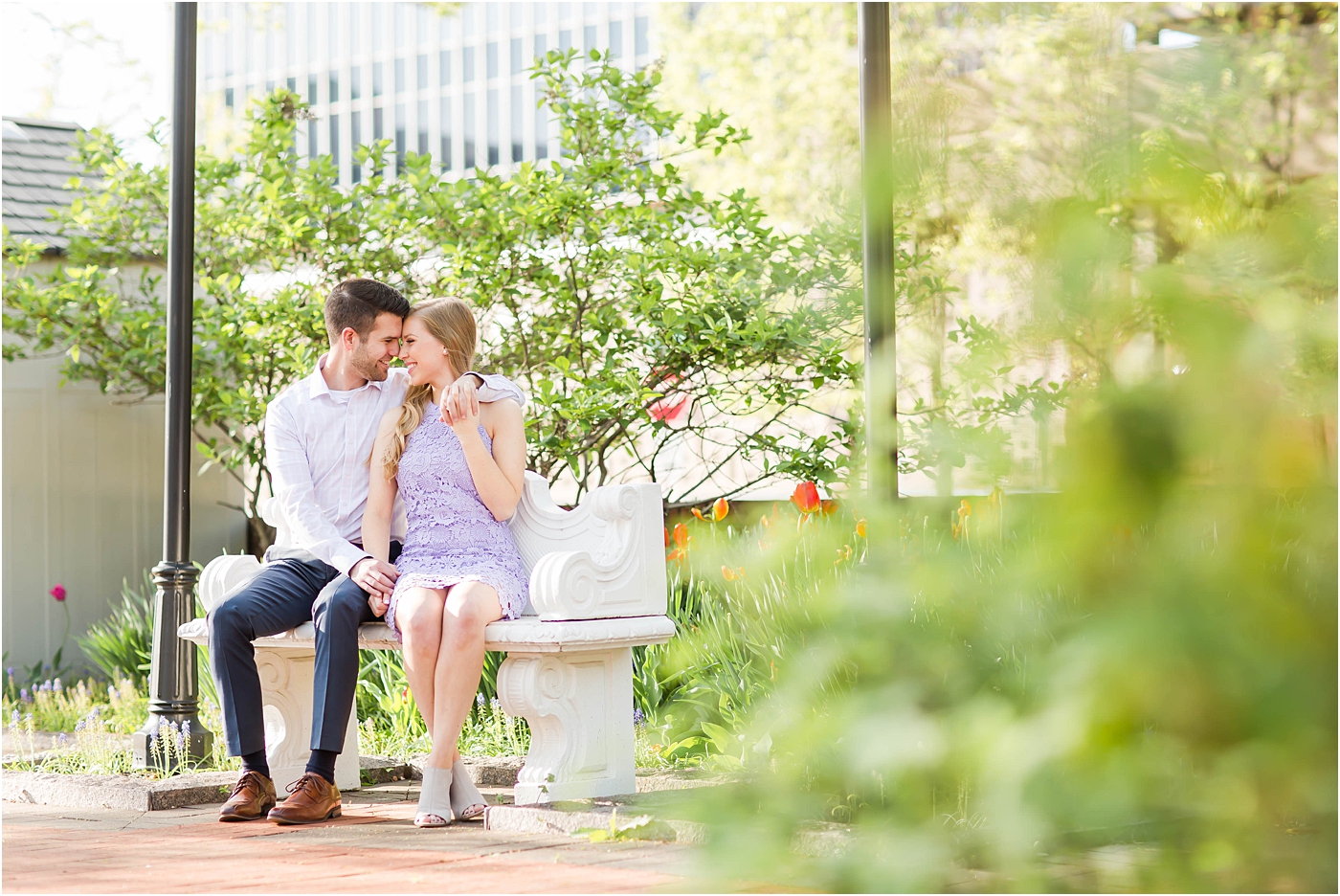 bride and groom sitting on park bench in downtown canton for their engagement session with akron wedding photographer