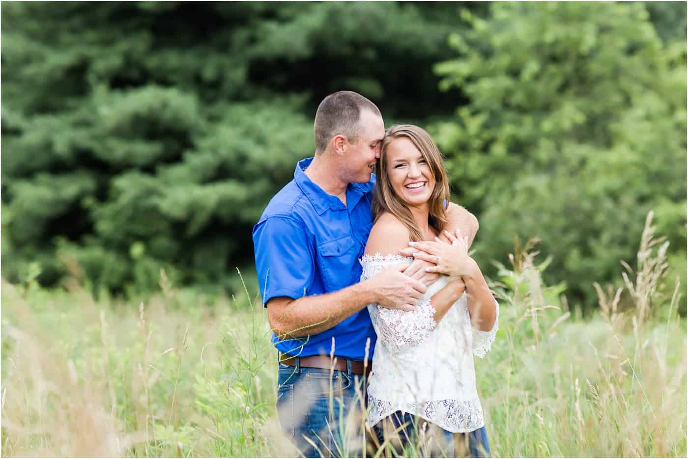Groom wrapping his arms around his bride-to-be while she laughs at their silver creek metro park engagement session photographed by akron wedding photographer loren jackson photography