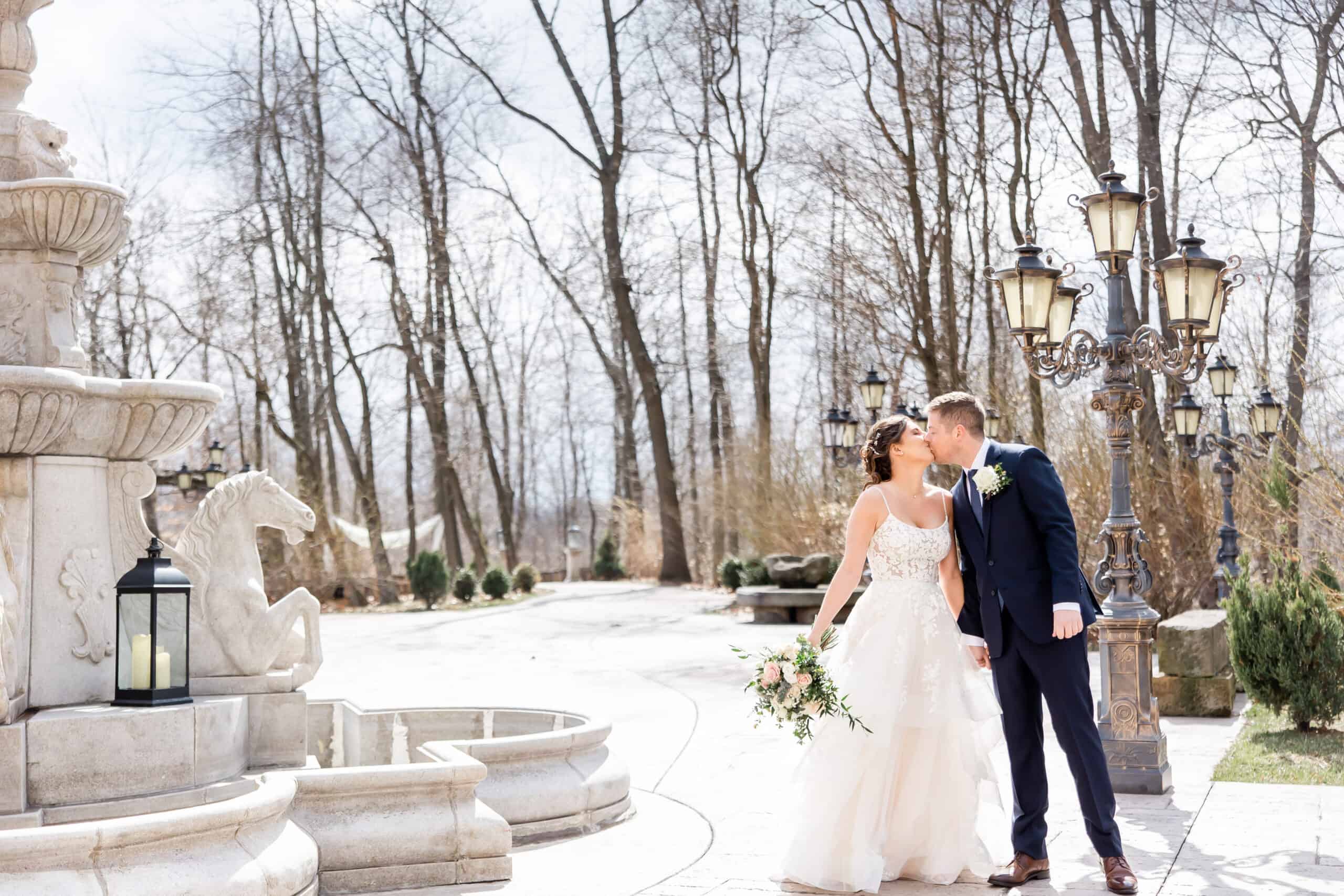 Snowy wedding day at bella amore with bride and groom standing by fountain