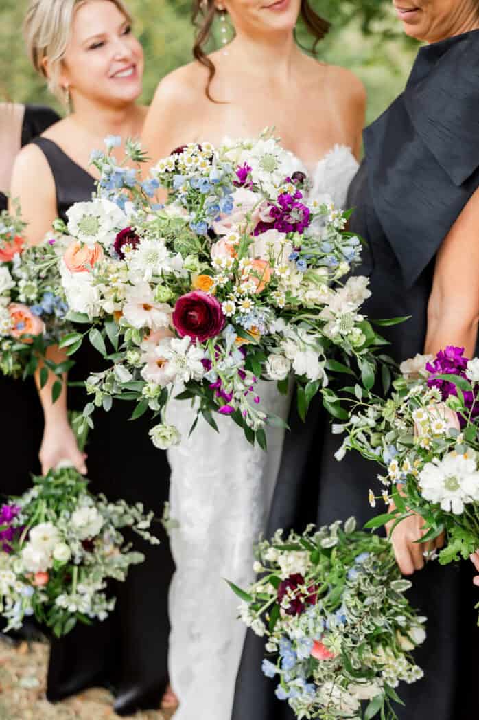 Bridal party holding coordinated wildflower-style bouquets at Rivercrest Farm wedding with soft pastel and vibrant floral details
